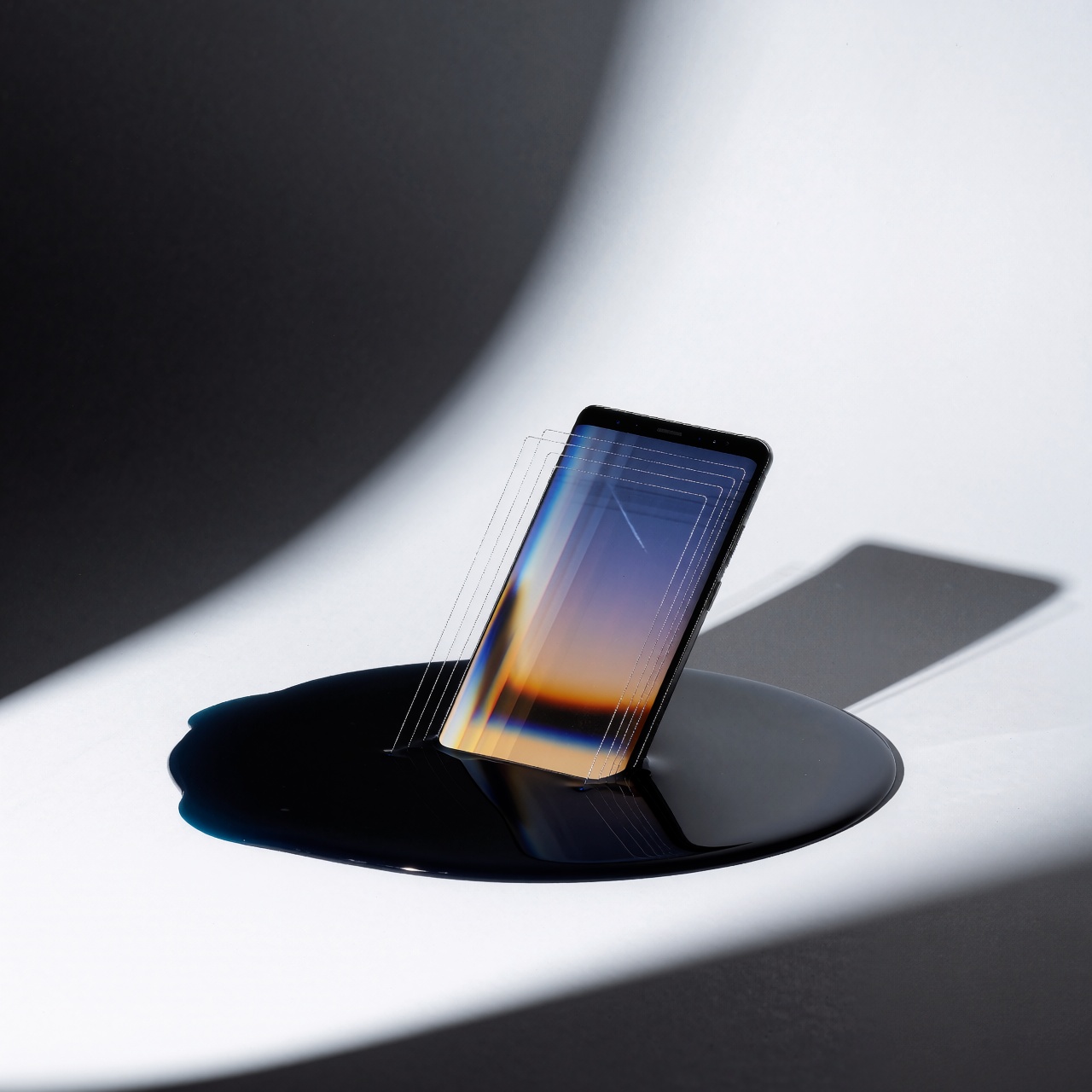 Samsung KNOX : la faille critique qui menaçait des millions de Galaxy pendant huit ans — image3 Un Galaxy Note 9 partiellement immergé dans un liquide sombre, reflétant des couches de lumière déformée. Arrière-plan blanc et lumière directionnelle acérée, soulignant la vulnérabilité des systèmes surprotégés. ---